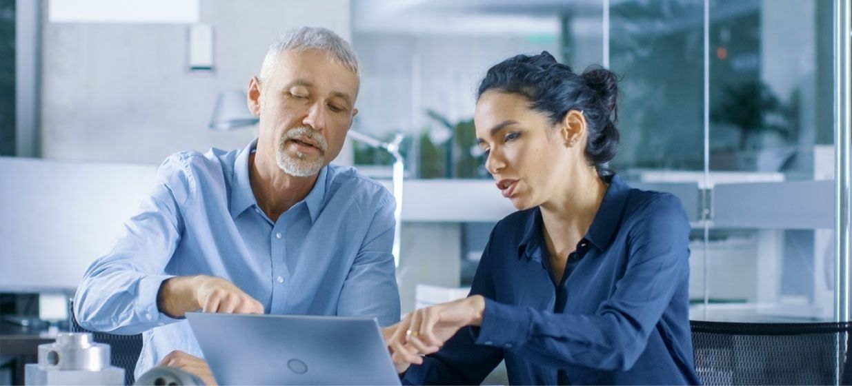 business man and woman reviewing consulting plans on laptop